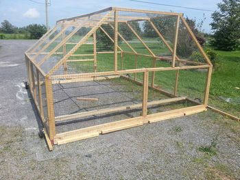 a small wooden chicken coop sitting on top of gravel