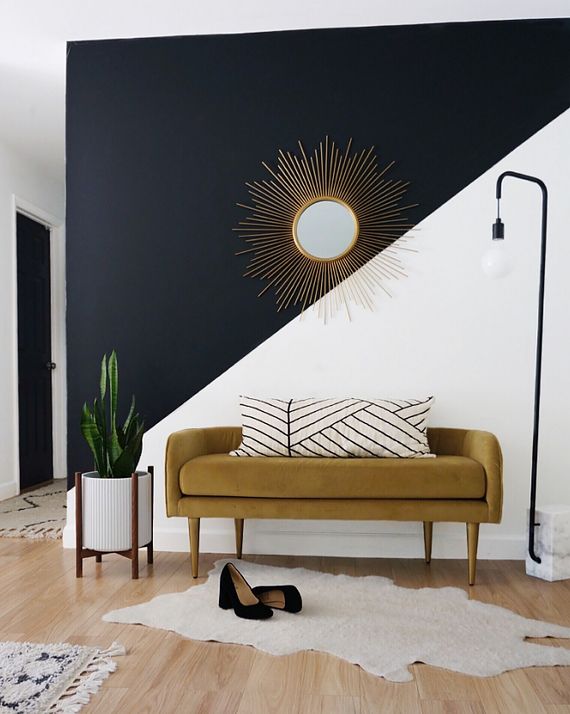 a couch sitting in front of a black and white wall with pink lettering on it