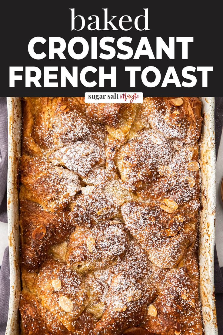 baked croissant french toast in a baking dish with powdered sugar on top