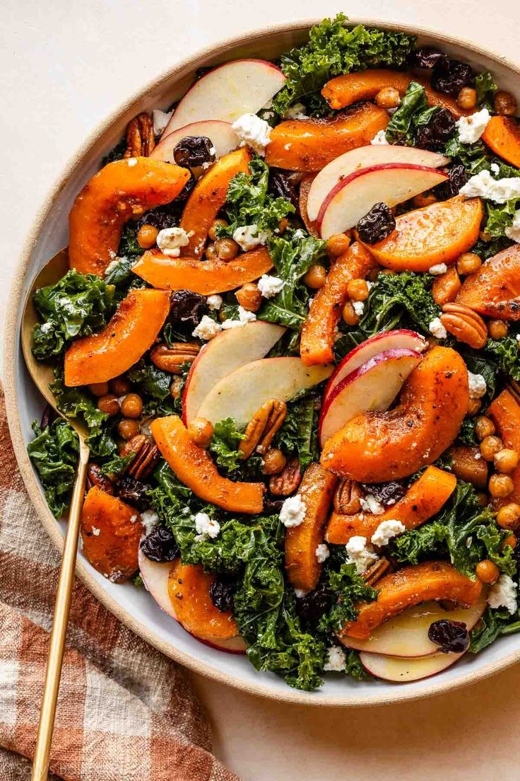 a salad with apples, carrots and nuts in a white bowl on a table