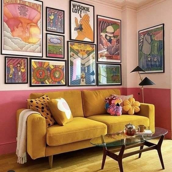 a living room with pink walls and pictures on the wall above it's couch