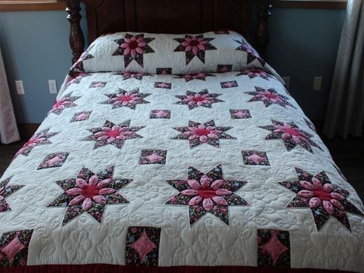 a quilted bed with pink and white flowers on it