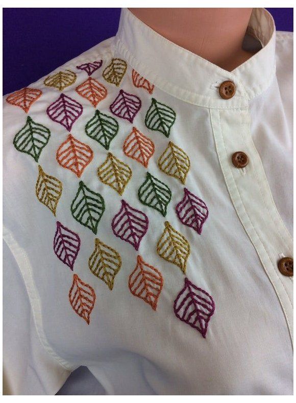 a white shirt with multicolored leaves on the chest and collar, along with buttons