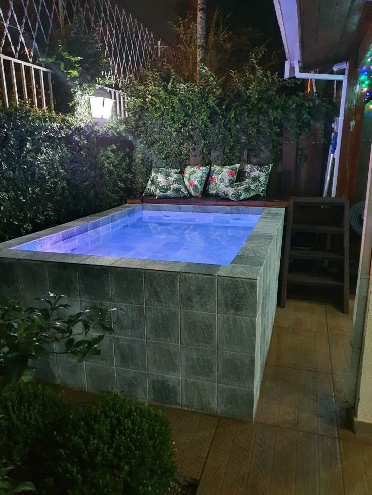 an outdoor swimming pool surrounded by greenery at night