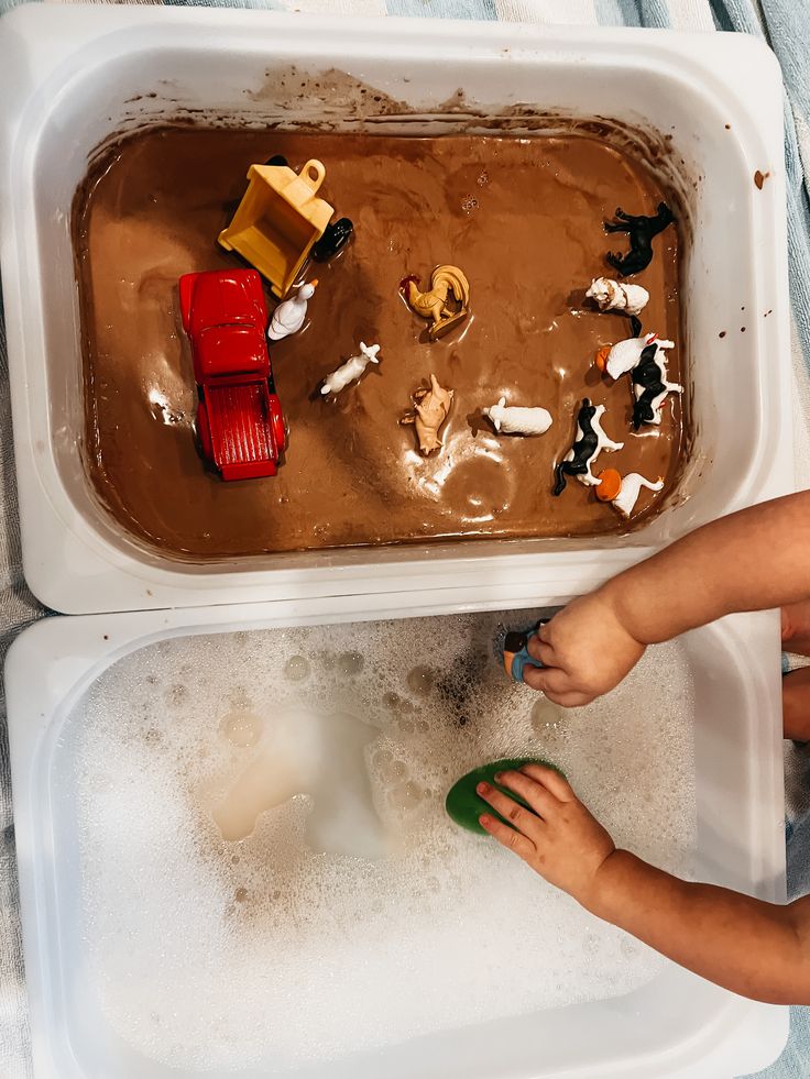 a young child playing with toys in a bathtub filled with water and dirt on the floor