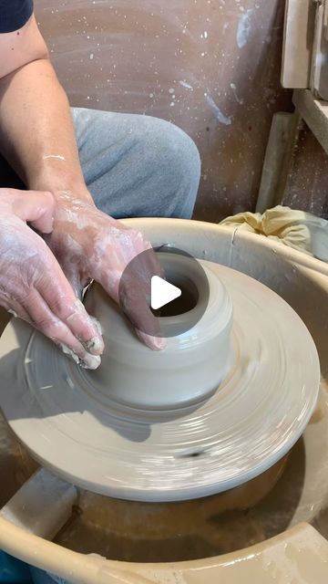 a woman is making a vase on a pottery wheel with one hand and the other