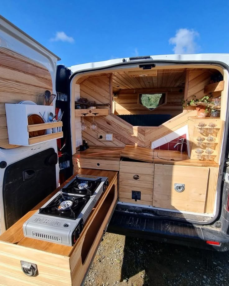 the back end of a van with its door open and drawers opened to reveal an oven