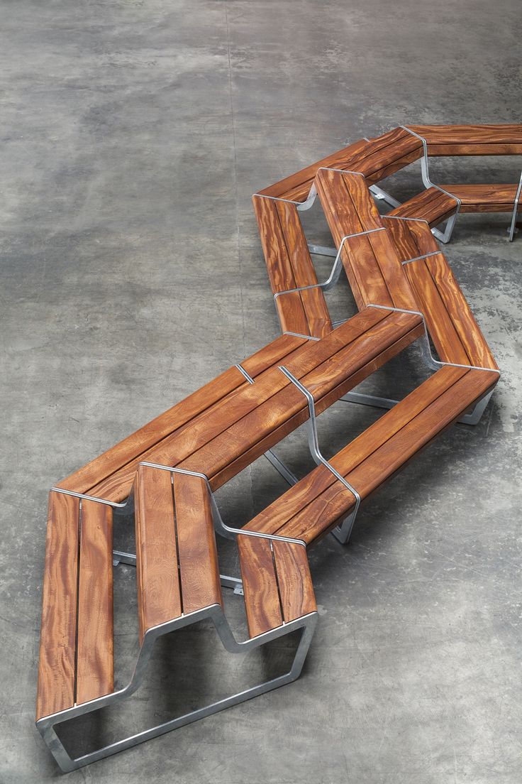 three wooden benches sitting next to each other on top of cement floored area with metal frame