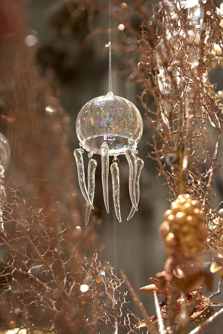 a glass ornament hanging from a tree in front of some branches and flowers