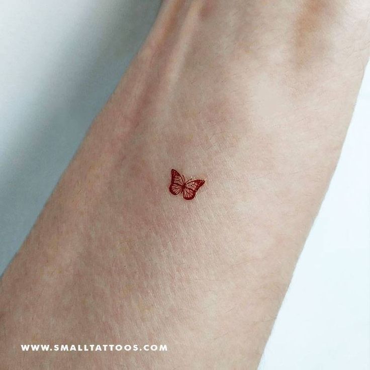 a small red butterfly tattoo on the wrist