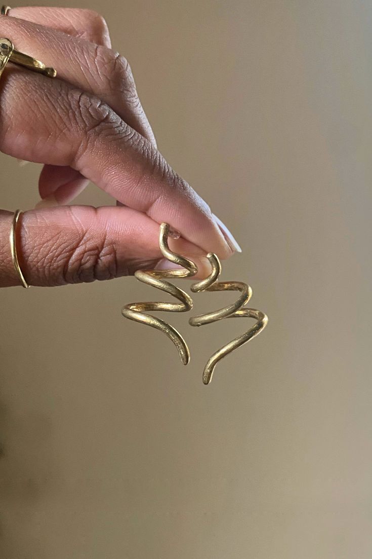 a woman's hand is holding some type of gold ring in her left hand