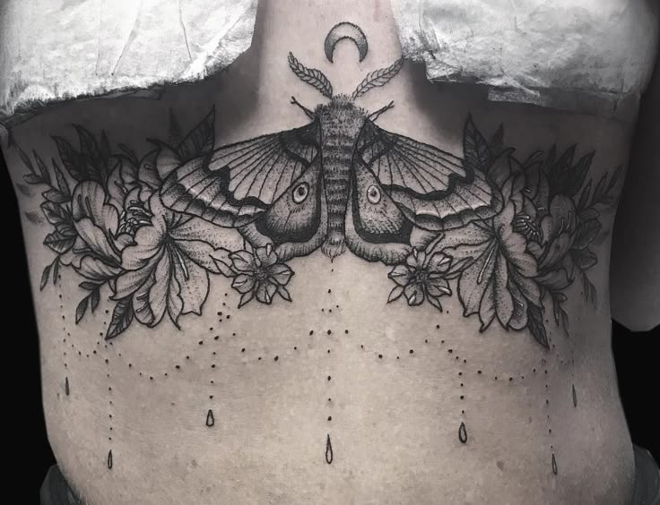 a woman's back with a moth and flowers on her lower back, in black and white