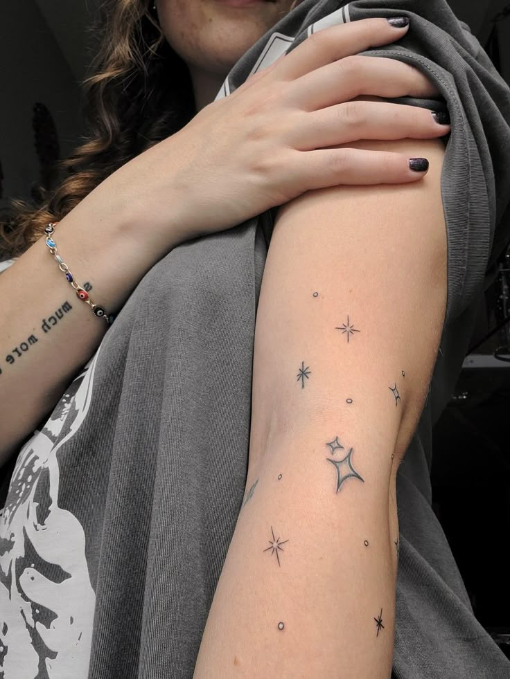 Star tattoo on arm Tiny Stars Tattoo Arm, Stars Around Moon Tattoo, Scattered Star Tattoos, Star Patchwork Tattoos, Sparkle Tattoo Sleeve Filler, Star Arm Wrap Tattoo, Anime Star Tattoo, Star Hip Tattoos Women, Star Arm Band Tattoo