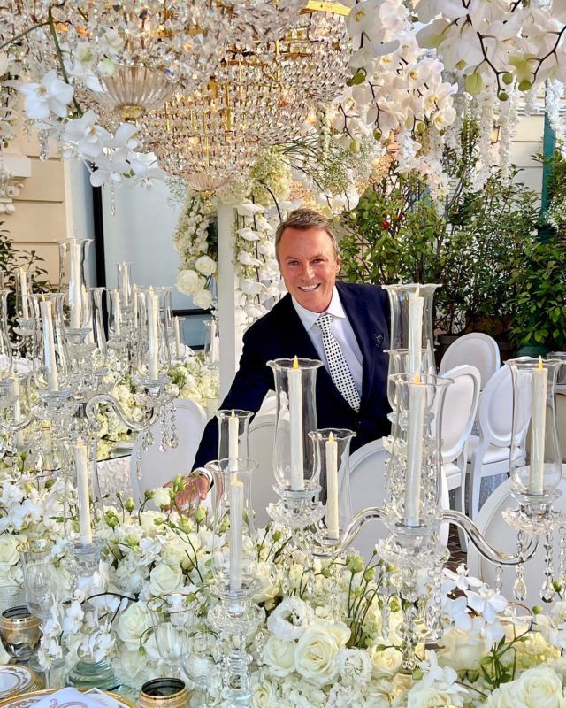 a man sitting at a table surrounded by white flowers