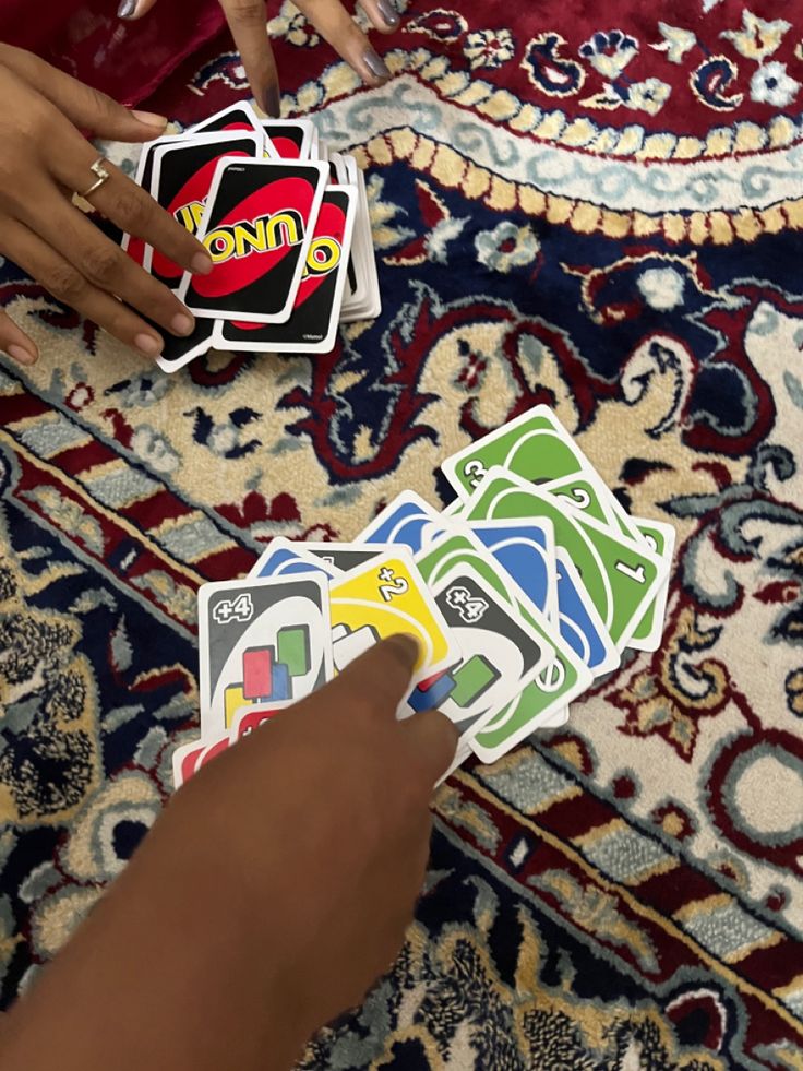 a person holding up several playing cards on top of a rug