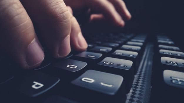 a person typing on a computer keyboard with their hand resting on the keypads