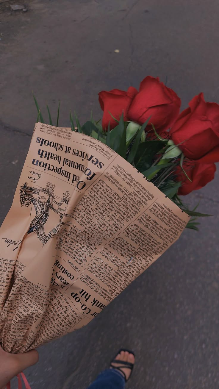 a person holding a newspaper with flowers in it