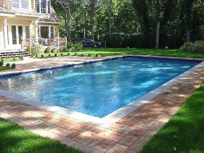 an empty swimming pool in the middle of a yard with grass and trees around it