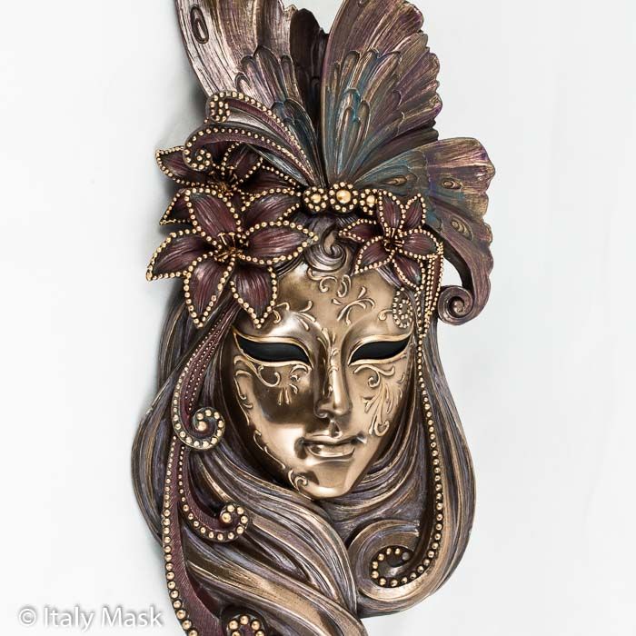 a woman's mask with long hair and butterfly wings on the face, made out of metal