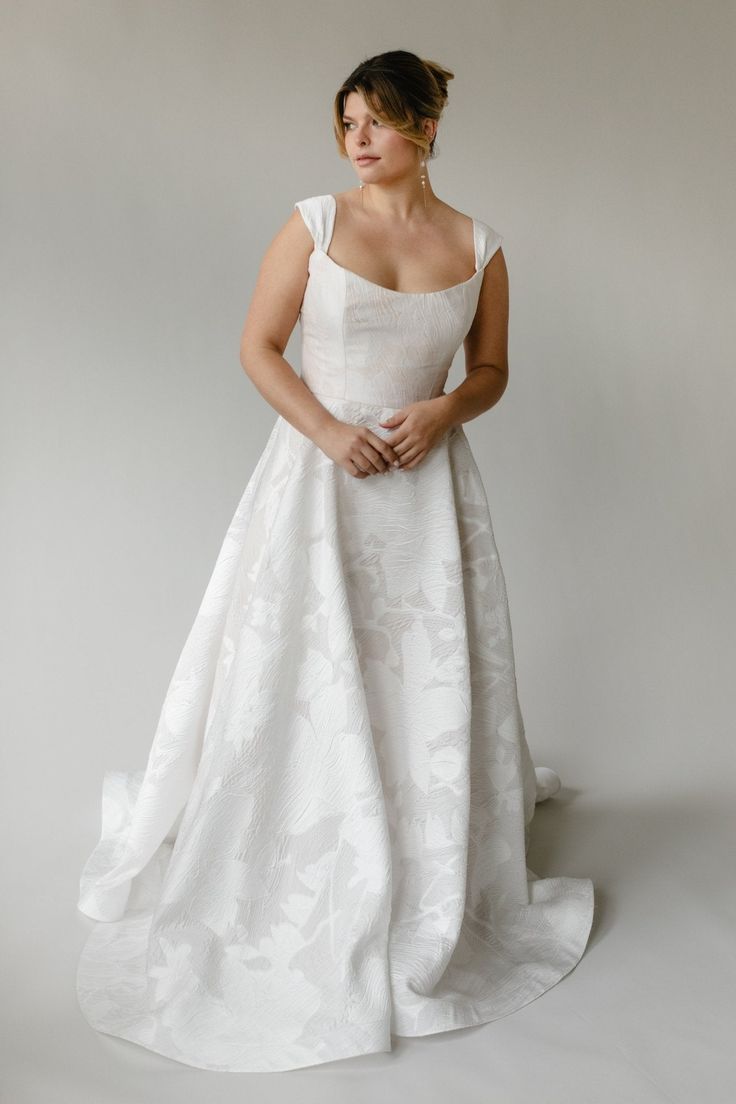 a woman in a white wedding dress posing for the camera with her hands on her hips