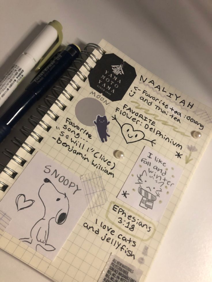 a notebook with some stickers on it next to a pen and paper clippings