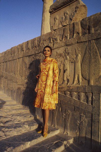 a woman standing in front of an ancient wall