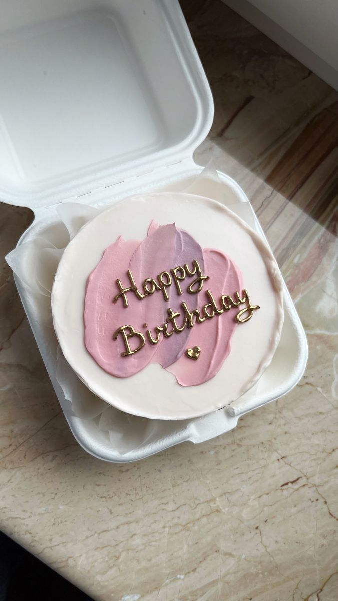 a birthday cake with pink frosting in a plastic container