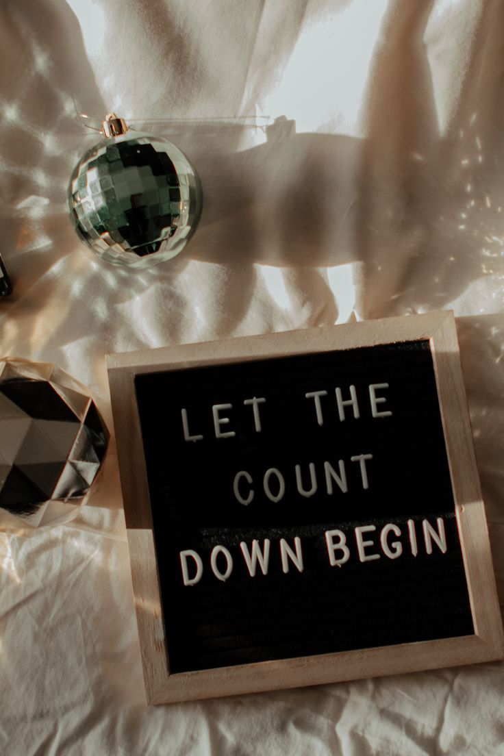 a sign that says let the count down begin next to some ornaments on a white sheet