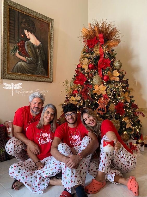 a group of people in matching pajamas sitting next to a christmas tree