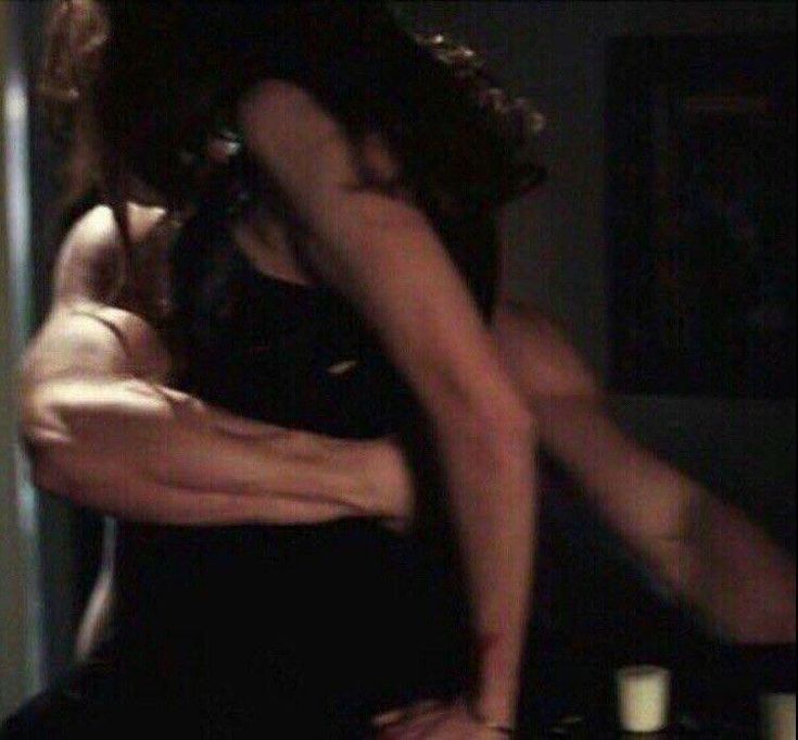 two people are dancing in the dark with their arms around each other and one person is holding another