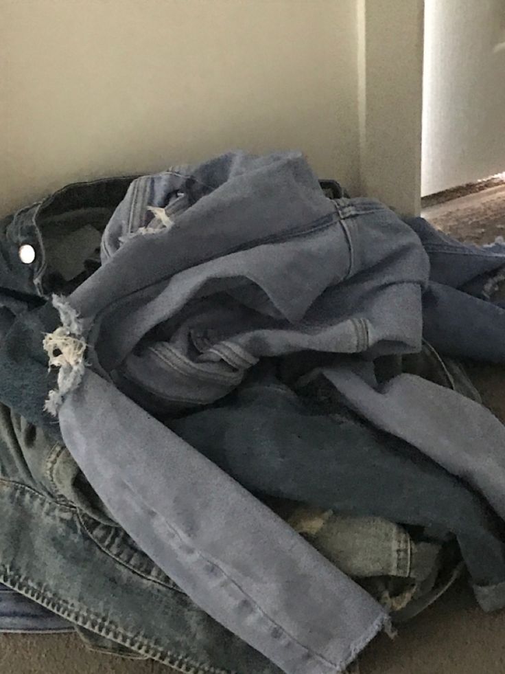 a pile of jeans sitting on top of a floor next to a wall and door