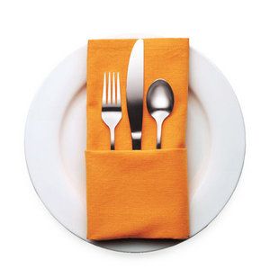 a white plate topped with silverware next to an orange napkin