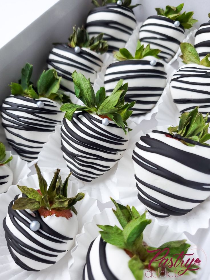 chocolate covered strawberries with black and white stripes are arranged in a row on top of each other