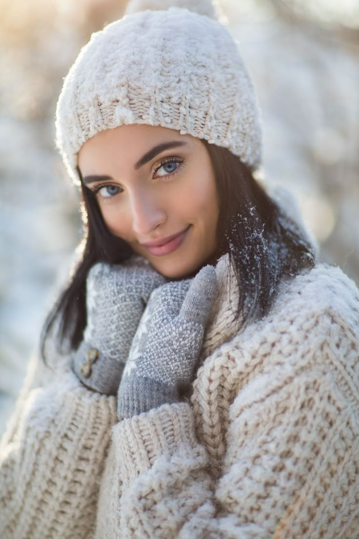 a woman wearing a white hat and mittens posing for a photo in the snow