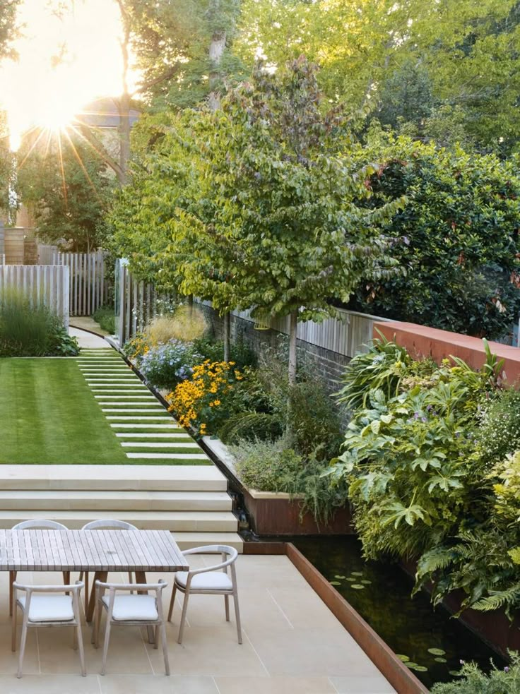 an outdoor dining table and bench in the middle of a garden