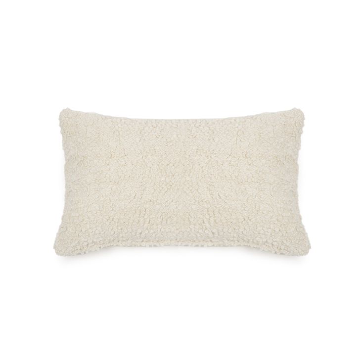 a white pillow with fluffy fur on the front and back, sitting against a white background