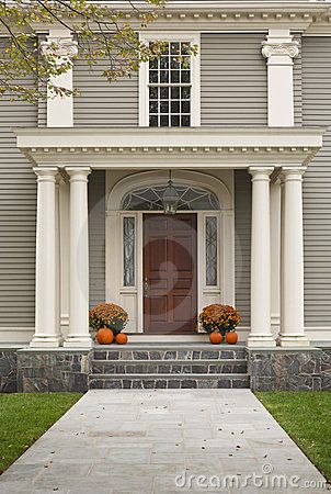 the front entrance to a house with two pumpkins on the steps