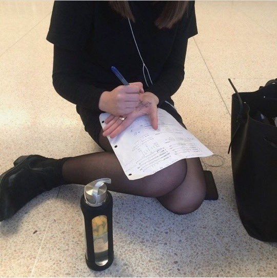 a woman sitting on the floor with her legs crossed and holding a pen in her hand