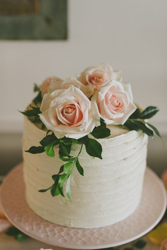 a white wedding cake with pink roses on top