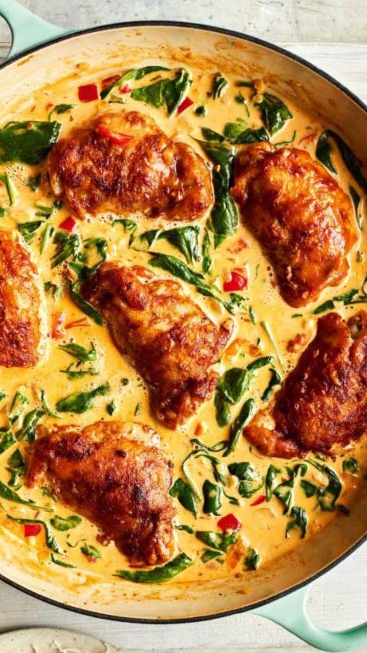 a pan filled with meat and vegetables on top of a white table next to utensils