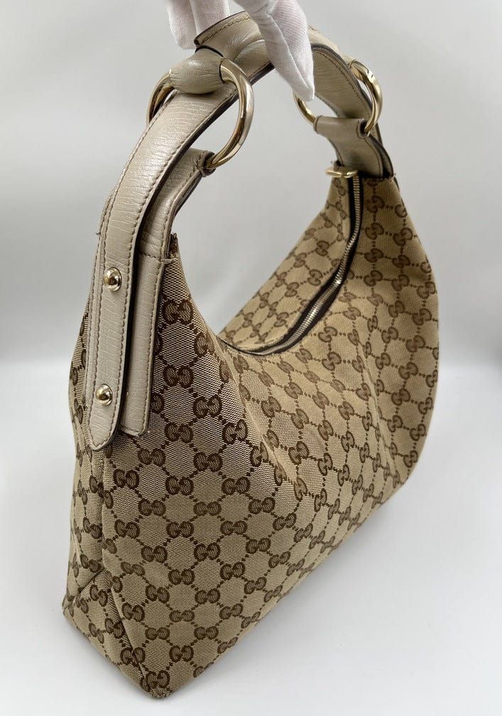 A stunning vintage Gucci hobo bag made from the iconic beige GG canvas with cream leather trim and pale gold hardware. Inside the bag is lined with a brown cotton lining and there is a zipped pocket for valuables. This bag is in excellent vintage condition, a true collectors item and comes with its original Gucci dust bag. There is some slight wear seen on the base corners. Luxury Gucci Calf Leather Shoulder Bag, Luxury Beige Bag With Horsebit Detail, Gucci Horsebit Bag 1955 Mini Beige, Luxury Brown Bag With Horsebit Detail, Luxury Vintage Bag With Horsebit Detail, Luxury Leopard Print Shoulder Bag With Leather Handles, Luxury Shoulder Bag With Gold-tone Hardware For Fall, Luxury Cream Hobo Bag For Daily Use, Luxury Tan Monogram Print Shoulder Bag