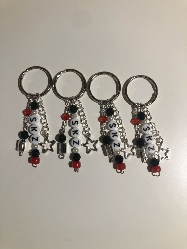 four key chains with charms attached to them on a white surface, one is red and the other is black