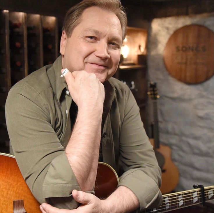 a man sitting in front of a guitar