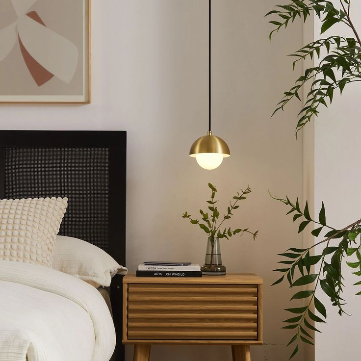 a bed room with a neatly made bed and a plant on the nightstand next to it