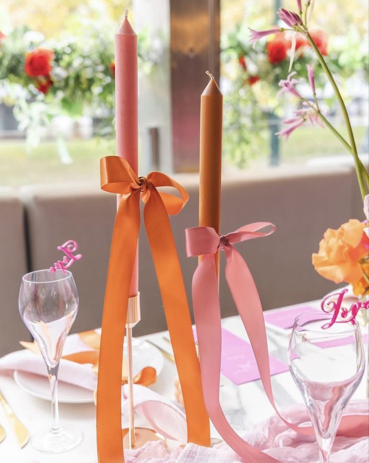 two candles with ribbons tied around them on a table