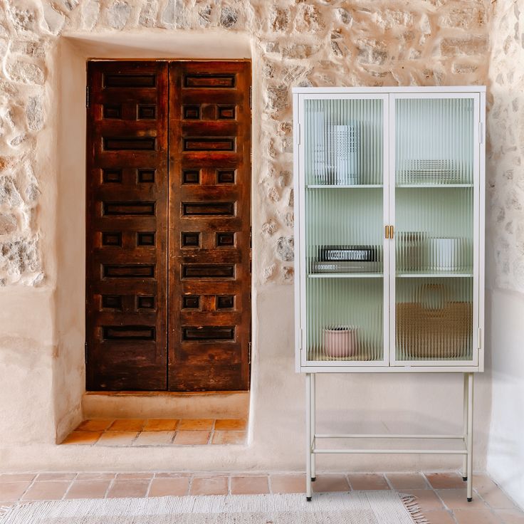 an open door to a stone building with a shelf below it and a basket in front of the door