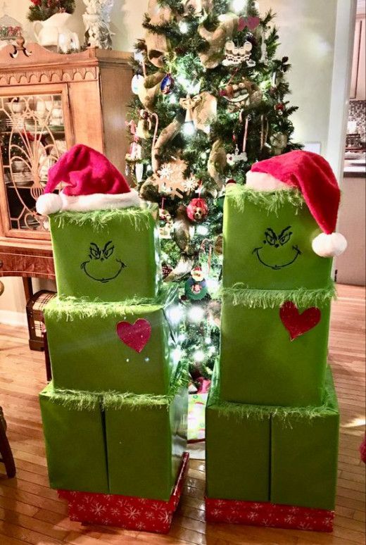 two green boxes with faces on them sitting in front of a christmas tree