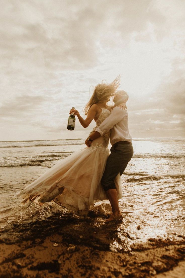 a bride and groom are kissing in the water on their wedding day at the beach