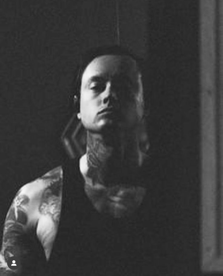 a black and white photo of a man with tattoos