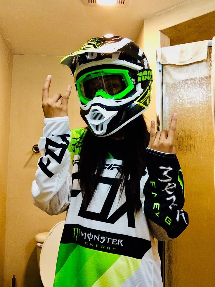 a woman in a helmet and goggles is making the peace sign with her hand